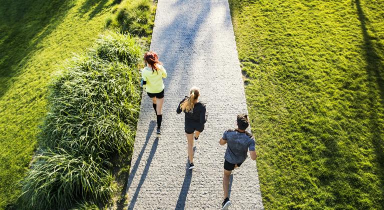 three people run along concrete walkway