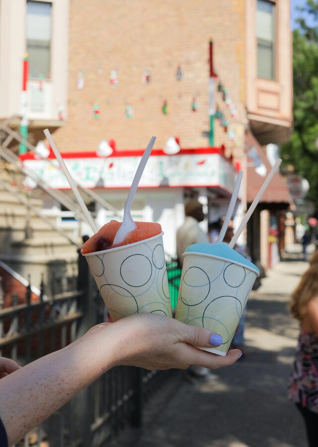 A hand holds two cups of flavored ice