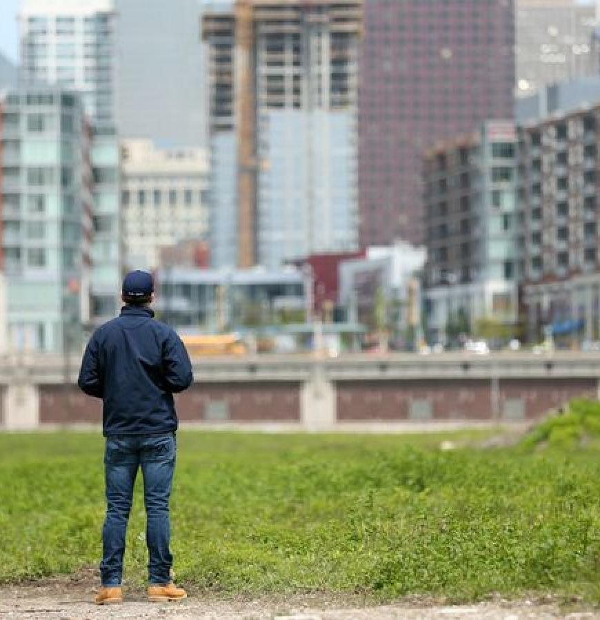 man with his back to the photographer stands in front of grassy area overlooking Chicago