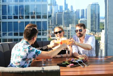 four people cheers on a roof top patio overlooking Chicago 