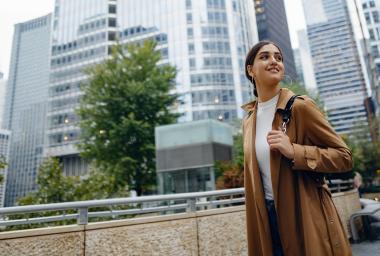 woman stands in front of tall buildings