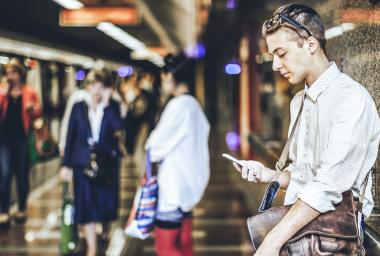 man leans against wall and looks at phone