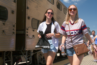 two women walk beside train at white sox station