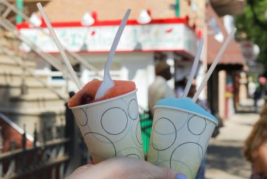 A hand holds two cups of flavored ice