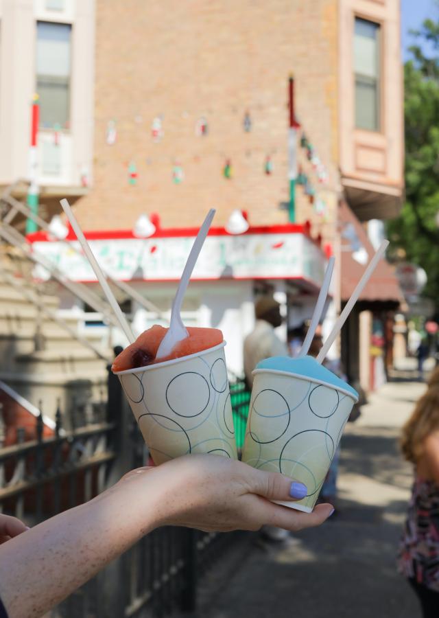 A hand holds two cups of flavored ice