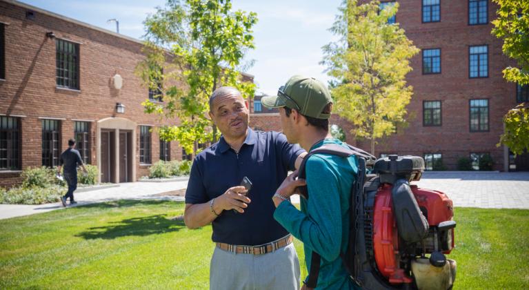 two people speak in front of brick buildings