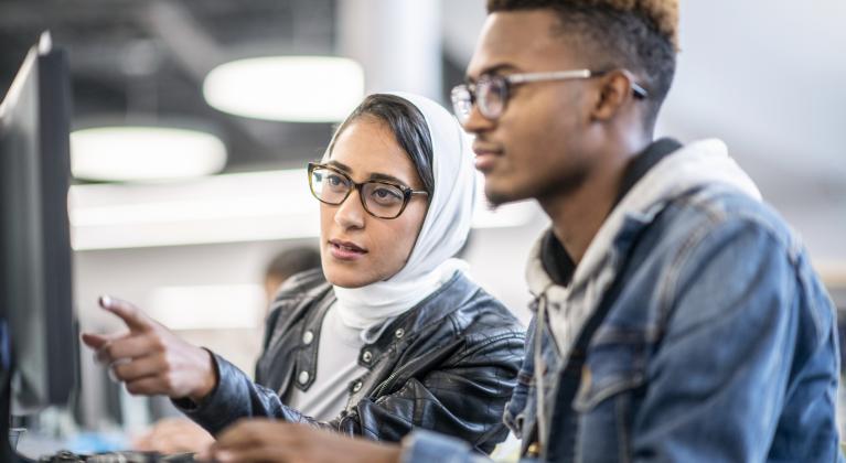 two people look at computer together