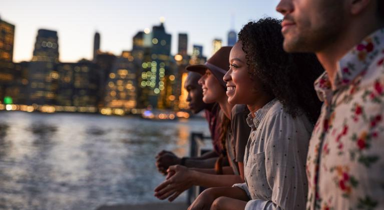 people stand in a row overlooking water