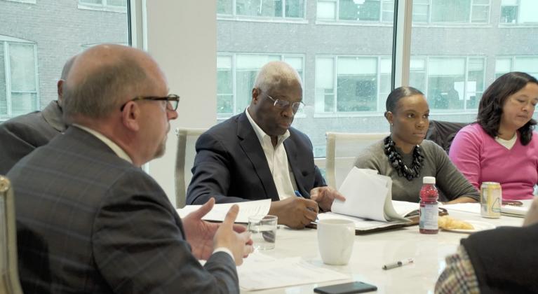 people sit around table with papers in front of them