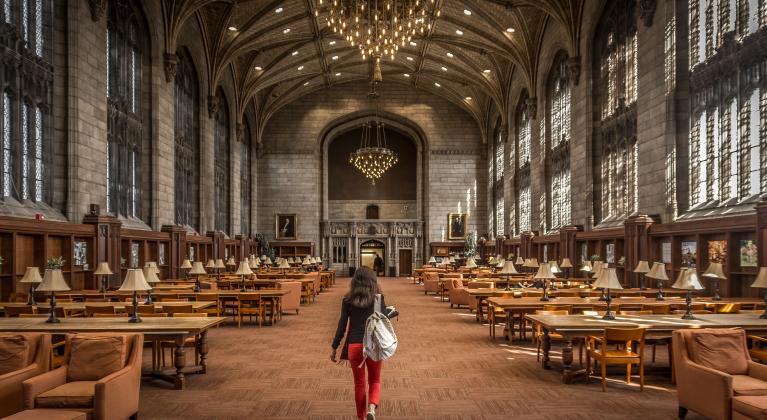 A woman walks through a large stone hall